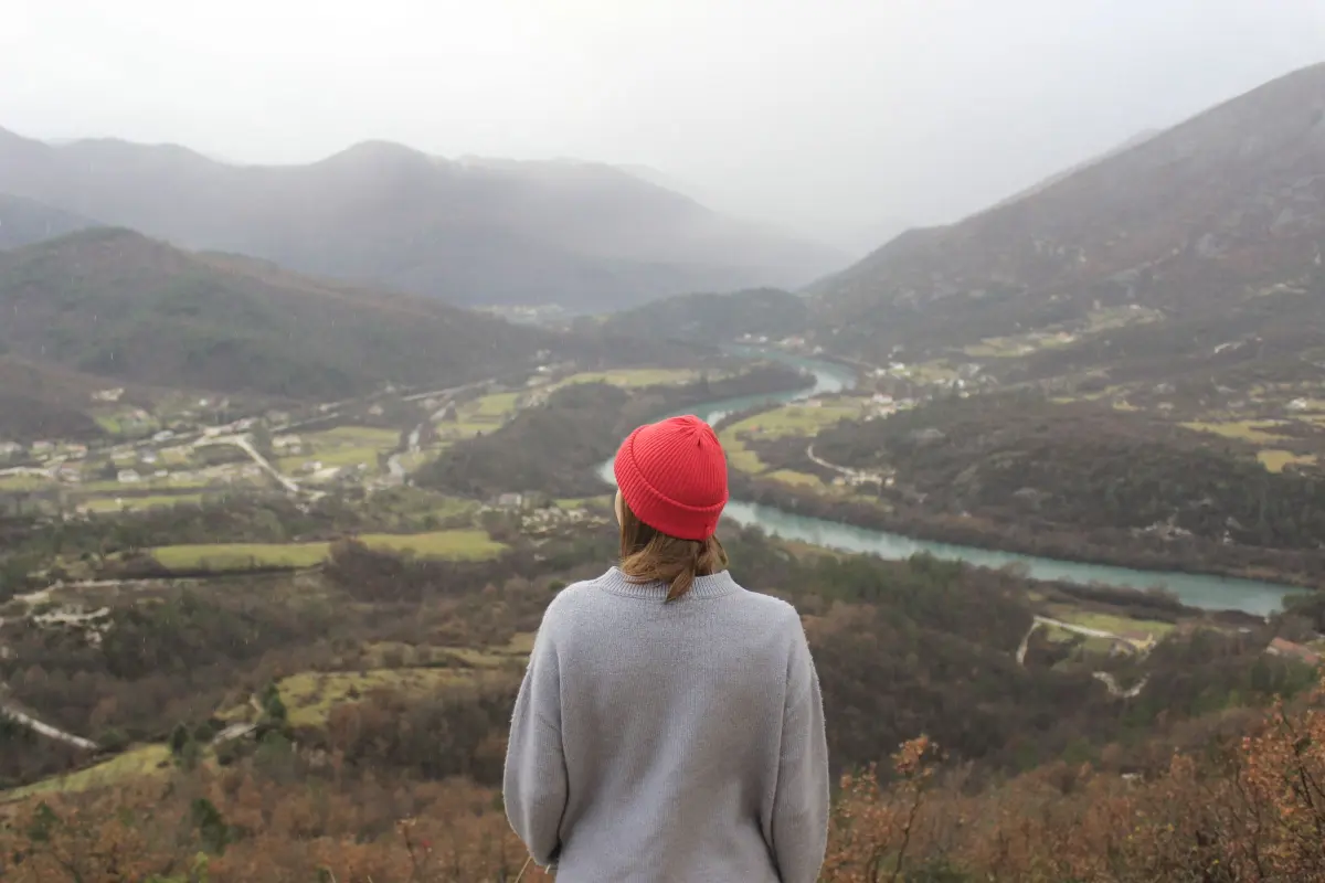 Viaggiatrice di spalle che guarda una valle tra le montagne