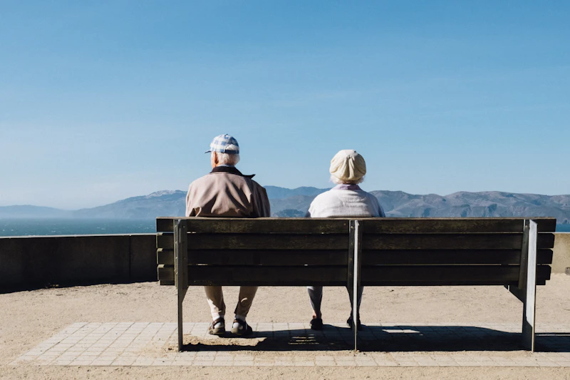 Due persone anziane sedute su una panchina davanti al mare
