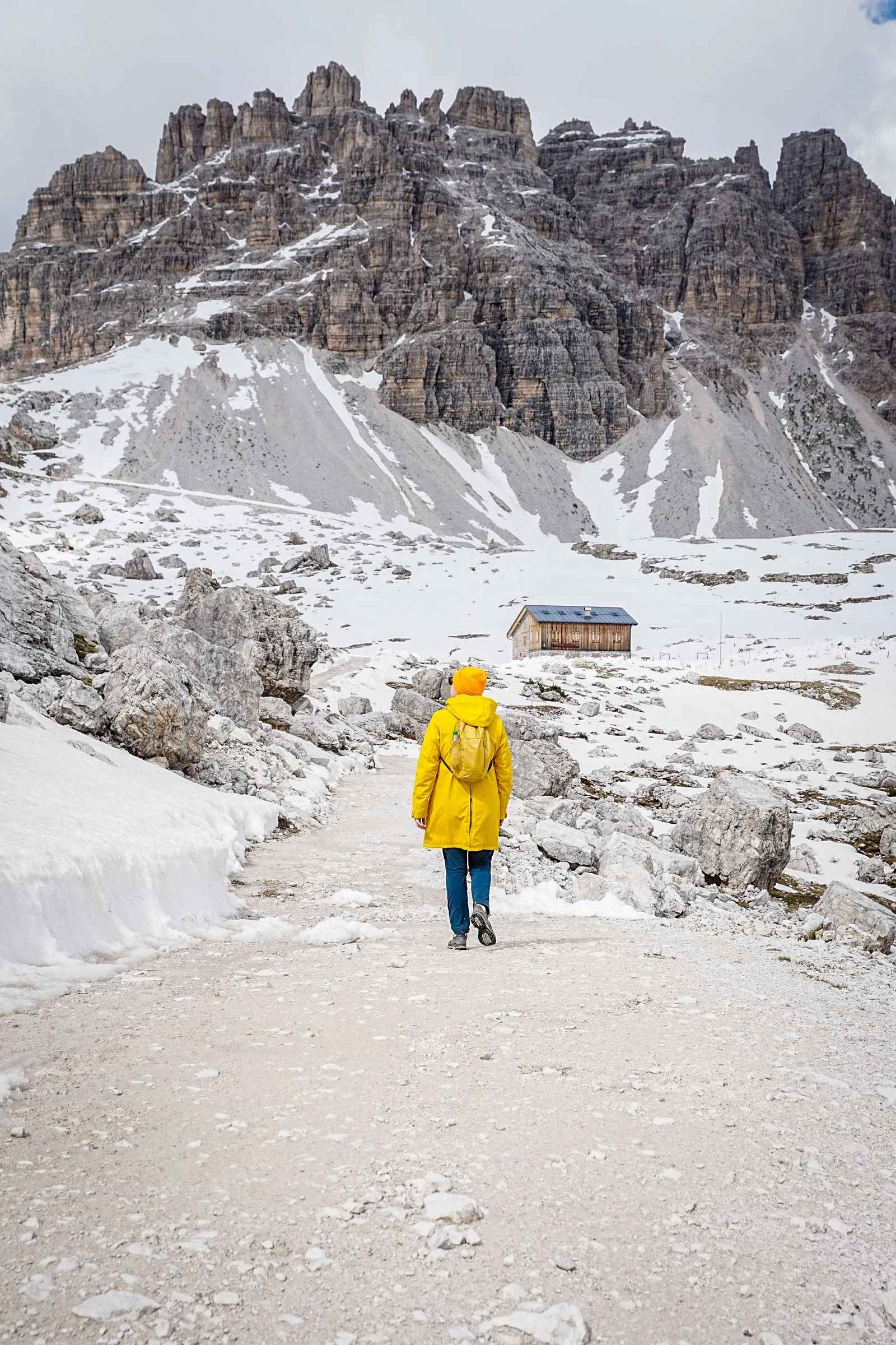 Escursionista su un sentiero delle Dolomiti vicino a un rifugio